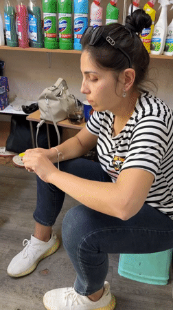 Woman sits on stool in cluttered Tashkent room