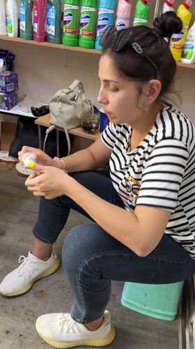 Woman sits on stool in cluttered Tashkent room