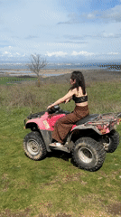 Woman poses with pink quad bike on Bulgarian coastal hill