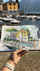 Watercolor sketch of lakeside buildings, held up in Mandello del Lario