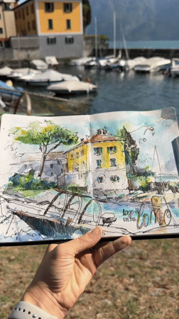 Watercolor sketch of lakeside buildings, held up in Mandello del Lario