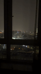 Nighttime city skyline filmed through window, camera pans right