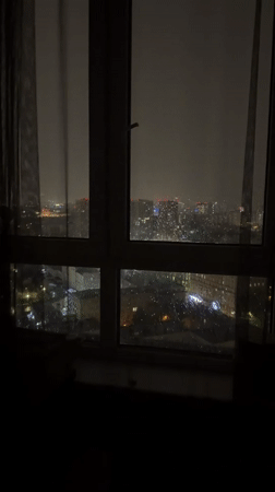 Nighttime city skyline filmed through window, camera pans right