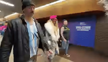 Three people walk through busy New York transit hub