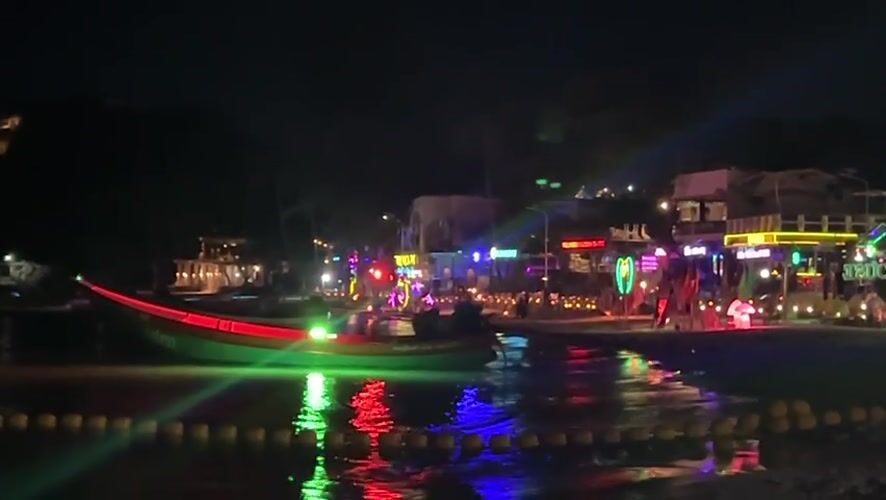 Nighttime beach yoga session captured in Thai tourist district