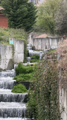 Children navigate homemade tree obstacle course near artificial waterfall