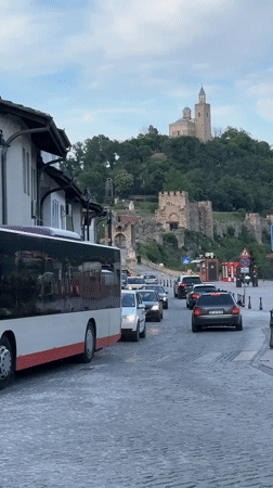 Tourist documents historic Veliko Tarnovo during evening hillside tour