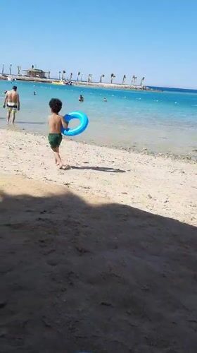 Boy walks across sunny beach in Hurghada, Egypt