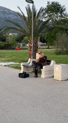 Street musician performs lute on park bench in Bar