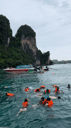Snorkelers and paddleboarders fill a turquoise bay near Ao Nang