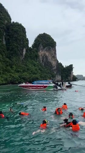 Snorkelers and paddleboarders fill a turquoise bay near Ao Nang