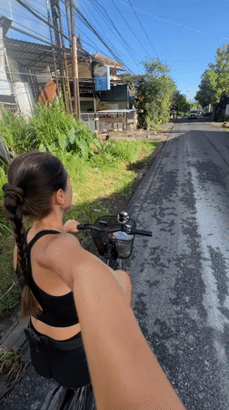 Woman cycles through wet Ubud streets at night