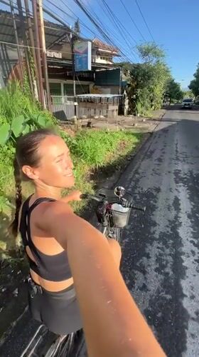 Woman cycles through wet Ubud streets at night