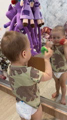 Child plays with mirror reflection using toy fruit