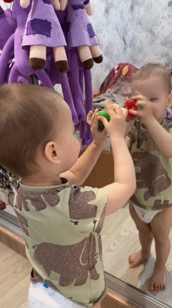 Child plays with mirror reflection using toy fruit