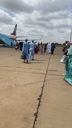 Traditionally dressed group boards a plane on a Nigerian tarmac