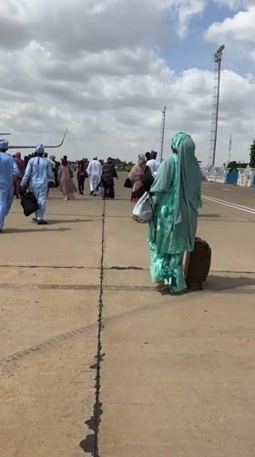 Traditionally dressed group boards a plane on a Nigerian tarmac