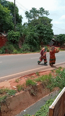 Traditional Igbo masqueraders walk paved road in Nkpor, Nigeria