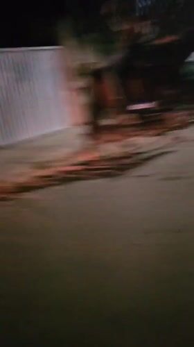 Young adults ride horses through nighttime streets in Cabo Frio