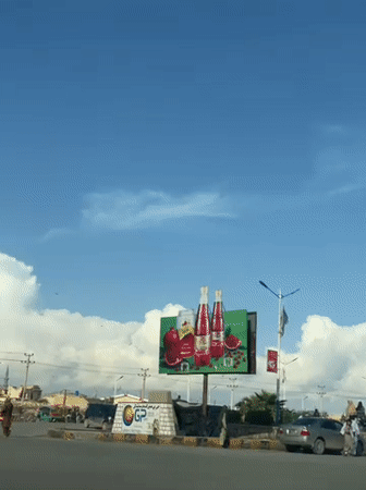 Normal traffic flows past clock tower in Kandahar