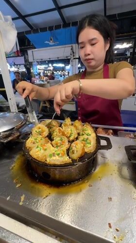 Street food vendors serve diverse dishes at Bangkok market
