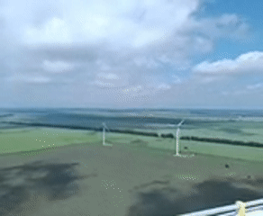 Person spotted resting atop wind turbine in rural area