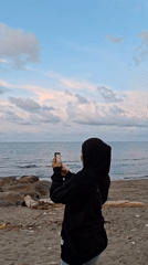 Beachgoers photograph ocean views in Lhokseumawe, Indonesia