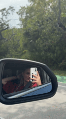 Woman takes selfie in car mirror while driving