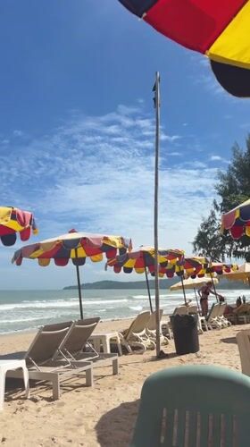 Colorful beach umbrellas shade lounge chairs in Choeng Thale