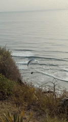 Paraglider flies over Mediterranean beach near Netanya during afternoon recreation