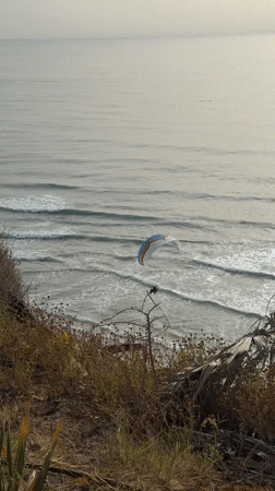 Paraglider flies over Mediterranean beach near Netanya during afternoon recreation