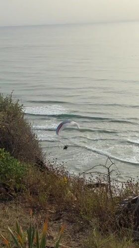 Paraglider flies over Mediterranean beach near Netanya during afternoon recreation
