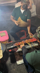 Street vendors grill satay at night in North Kuta