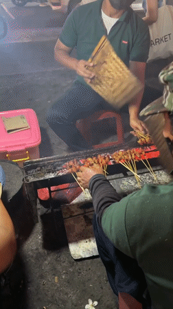 Street vendors grill satay at night in North Kuta