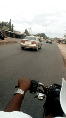 Motorcycle rider travels through morning traffic on city street