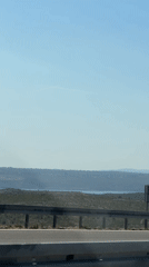 Driving Croatia's scenic coastal highway past rolling green hills