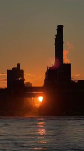 Sun sets between smokestacks at a New York power plant