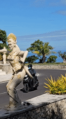 Traditional Balinese dancer statues line coastal road in Kuta Selatan