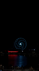 Late-night Ferris wheel glowing over a waterfront city at 3am
