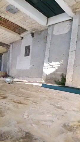 The video shows a first-person perspective walking down a set of outdoor stairs. The stairs are made of stone and concrete with some grass growing between the steps. There are stone walls on either side of the stairs, with a window with green shutters visible on one wall. The overall environment appears to be an old, weathered building.