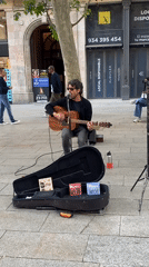 Barcelona street life: musician, plaza fountain, pedestrians under Catalan flag