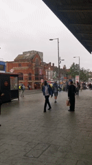 Pedestrians walk London sidewalk during overcast afternoon