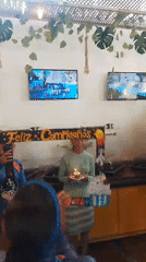 Women celebrate birthday with Spanish sign and cupcake indoors