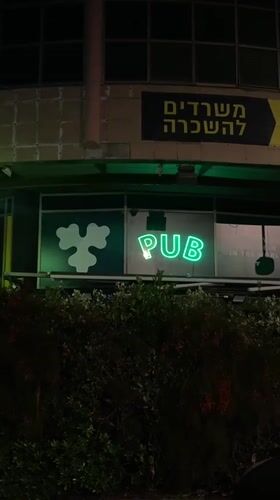 Neon pub sign cycles colors on Tel Aviv building
