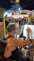 Street artist and evening crowds on Eilat's commercial strip