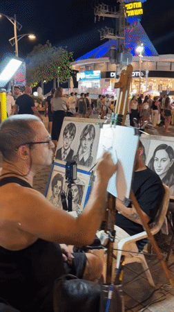 Street artist and evening crowds on Eilat's commercial strip