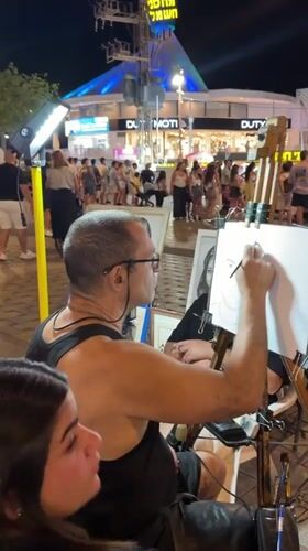 Street artist and evening crowds on Eilat's commercial strip