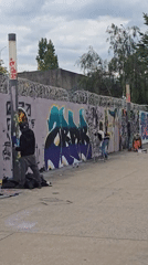 Three people spray paint graffiti on Paris wall