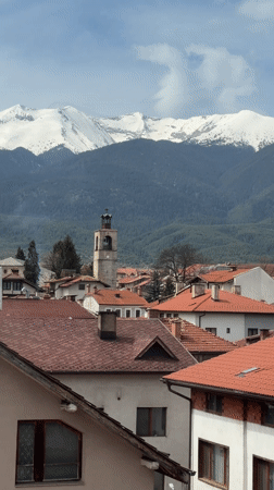 Aerial view captures Bansko's red rooftops against snowy mountains