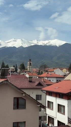 Aerial view captures Bansko's red rooftops against snowy mountains